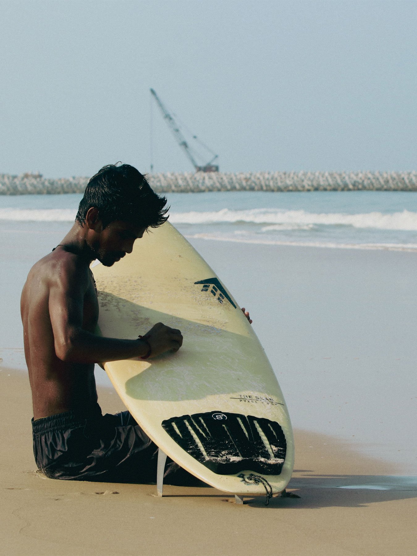 Young surfer carrying a surfboard near the shoreline